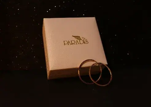 A cream ring box stamped in gold foil, two bands resting beside it.
