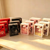 Set of pink, beige, red, and black window gift boxes with satin ribbon bows on a table