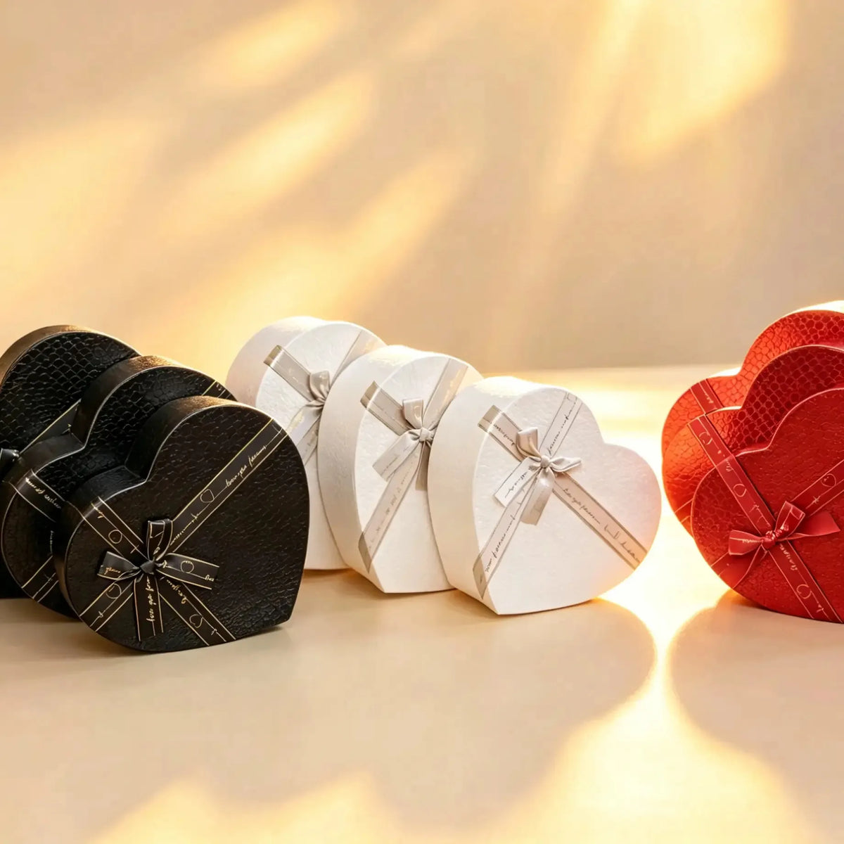 Black, white, and red heart-shaped gift box sets with satin ribbon bows shown together