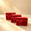 Three nested red velvet gift boxes with satin ribbon and bow, in graduating sizes on a table.