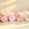 Set of three pink heart-shaped nested gift boxes with satin ribbon bows, next to peach, beige, and off-white sets