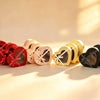 Heart-shaped gift boxes with ribbon bows in red, peach, gold, and black lined up together