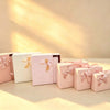 Pink, beige, and off-white pin-dot gift boxes with satin ribbon bows displayed together