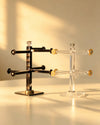 Clear acrylic and dark metal bangle display stands side by side, gold-tone arm caps