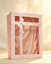 Blush pink gift box with clear window, satin ribbon bow, and pink fabric lining