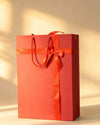 Red bag-style gift box with satin ribbon bow and rope handles