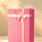 Pink bag-style gift box with pale pink ribbon bow and rope handles