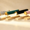 Four velvet-topped bangle stands in cream, teal, black, and pink, one holding stacked bracelets, on wood bases.