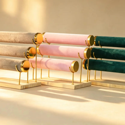 Three-tier bangle display stands in beige, pink, and dark green velvet with gold hardware