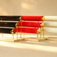 Three-tier bangle display stands in black, red, and ivory velvet with gold hardware