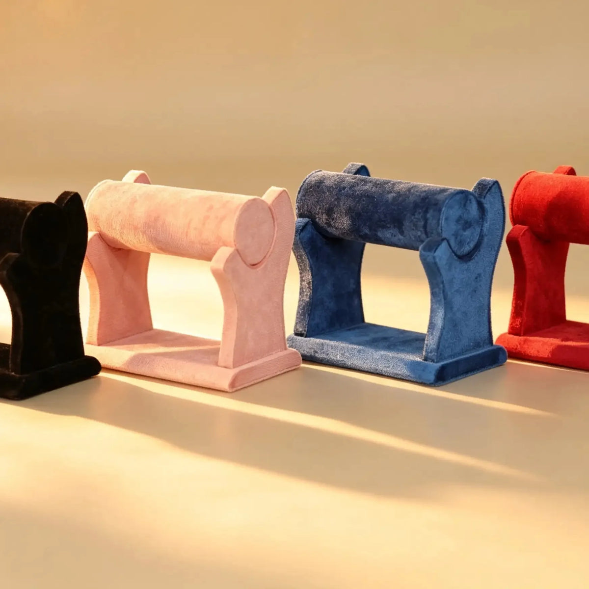 Four velvet bangle stands in black, pink, blue, and red lined up side by side
