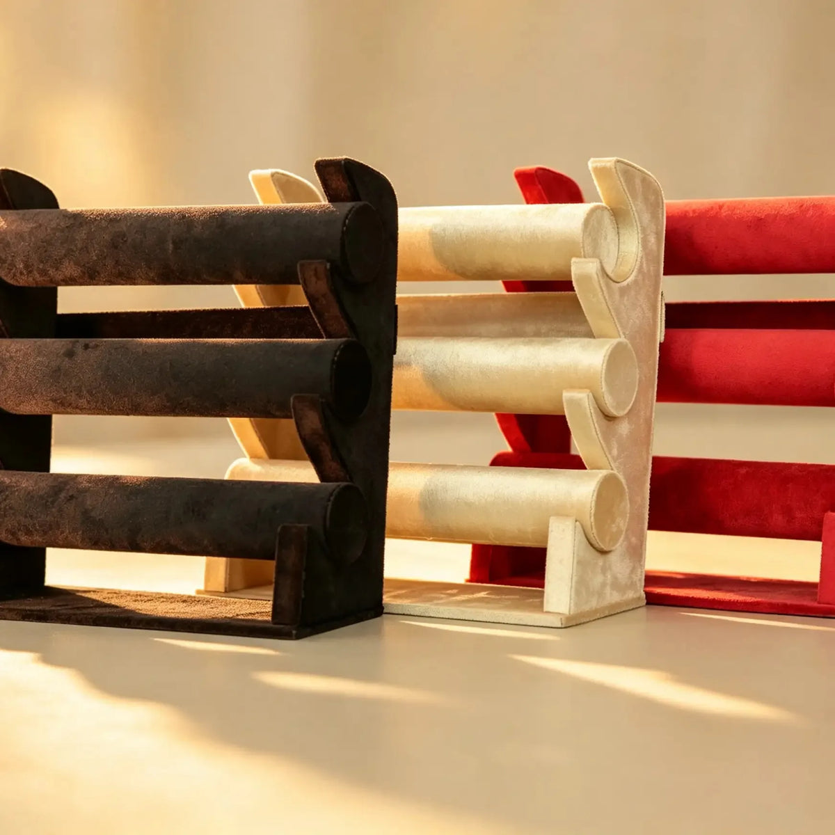 Three velvet bangle stands in dark brown, cream, and red, shown side by side