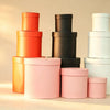 Red nested round gift boxes with lids, grouped with black, white, and pink sets