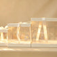 Three ivory-trimmed clear PVC cake boxes nested together with cream satin ribbon ties