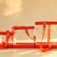 Three orange-trimmed clear PVC cake boxes nested together with orange satin ribbon ties