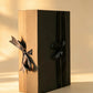 Black folding gift box with kraft-brown side panel and two black ribbon bows