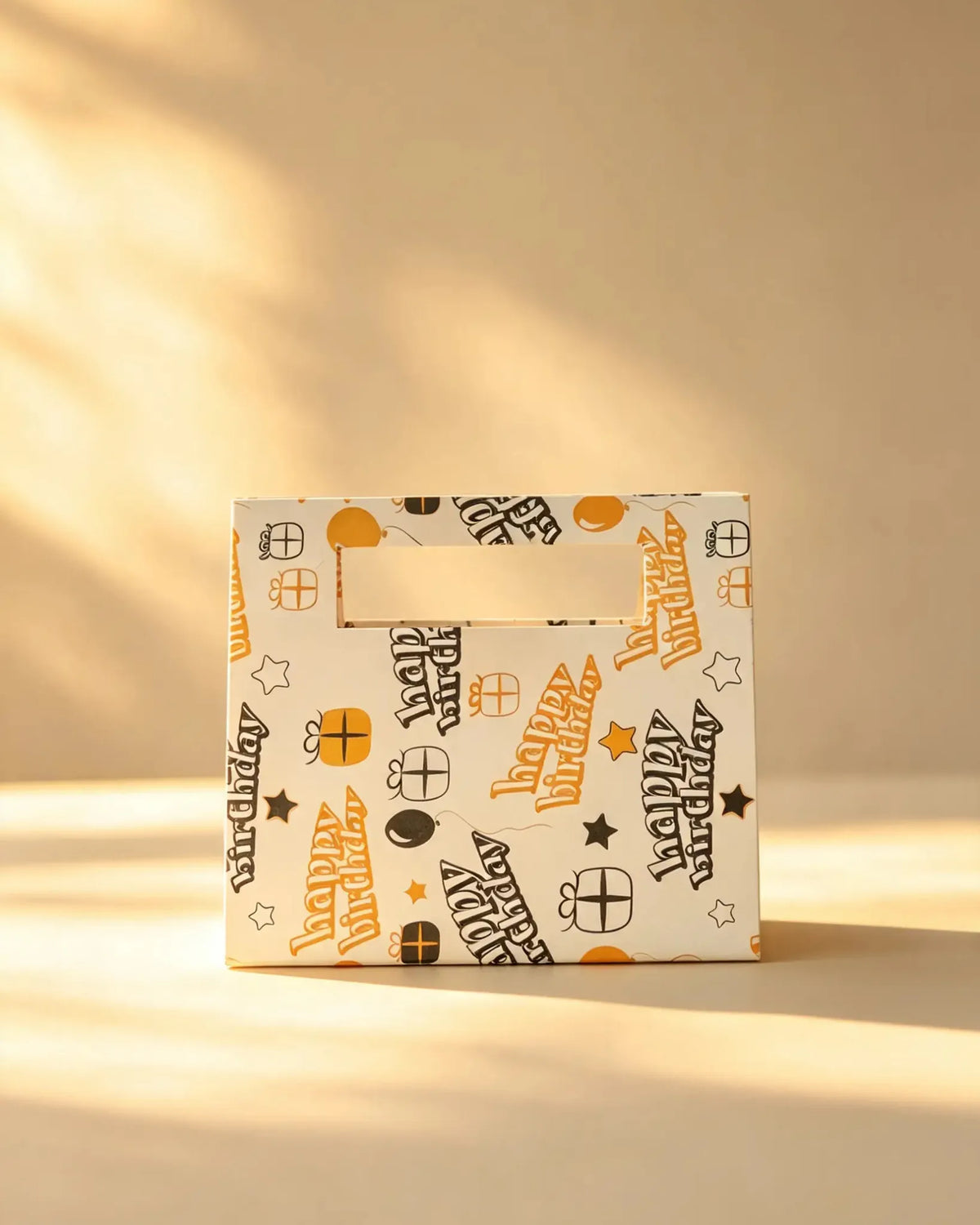 Cream gift bag printed with 'Happy Birthday' text and party icons, ribbon handle