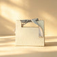 Ivory gift bag with a subtle tonal wave pattern and a grey ribbon bow handle