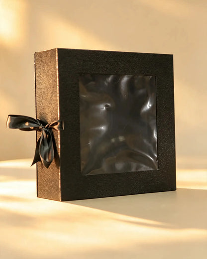 Black folding gift box with bronze side panels, clear window, and black ribbon bow