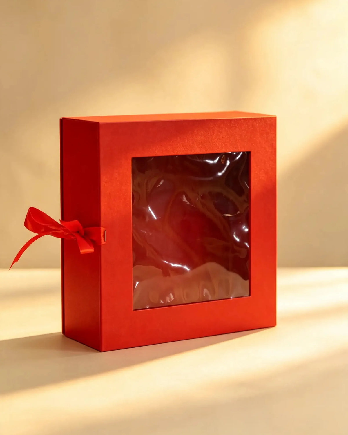 Red folding gift box with a clear front window and matching red ribbon bow
