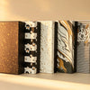 Row of five gift boxes in speckled, floral, and marbled foil-print patterns