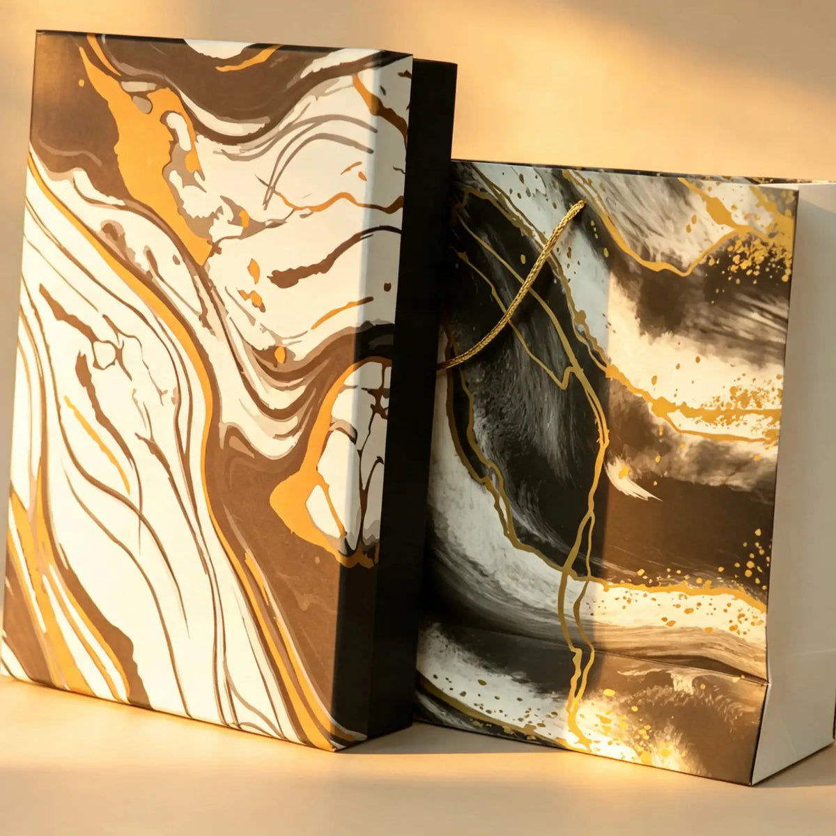 Brown marble-print gift box beside a matching black marble carry bag with gold cord handle