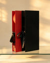 Black and red sliding gift boxes with satin ribbon bow ties, shown together
