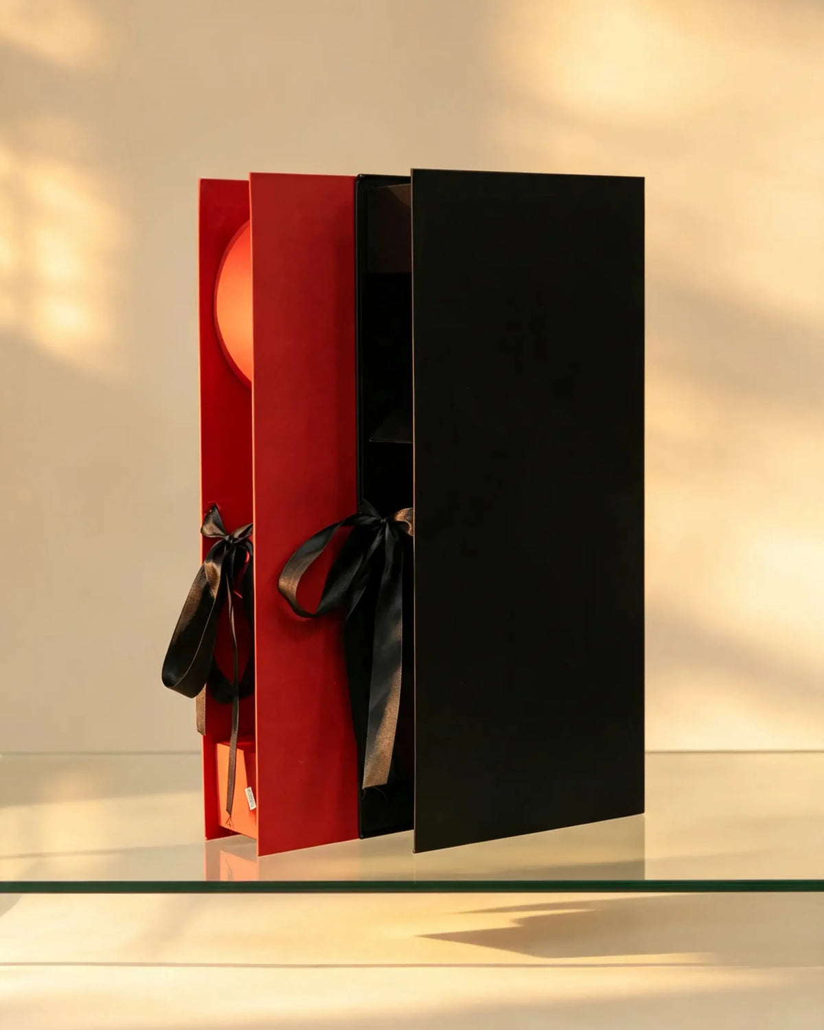 Black and red sliding gift boxes with satin ribbon bow ties, shown together
