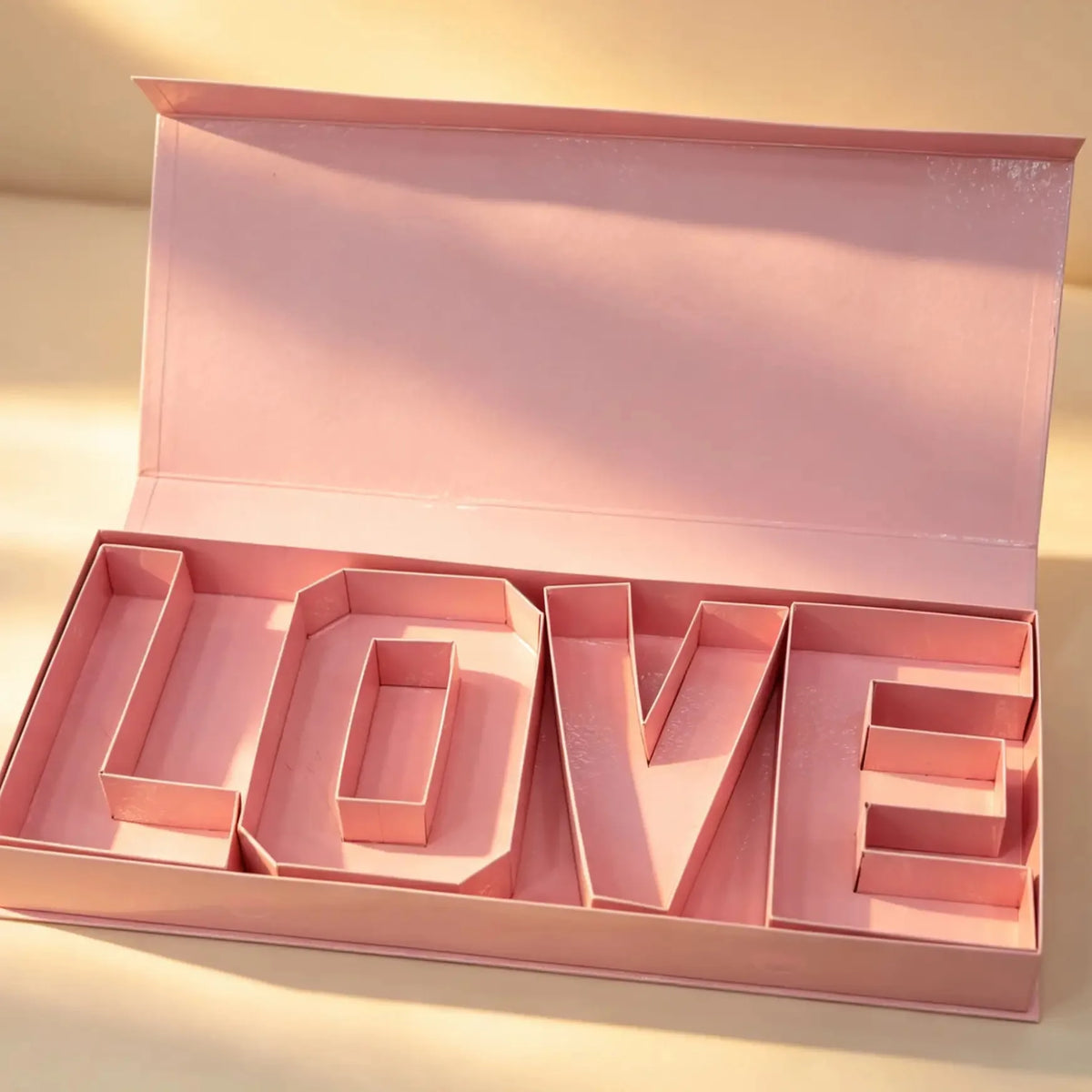 Open pink gift box revealing interior compartments shaped like the letters L-O-V-E