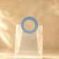 Clear PVC gift bag with round blue handle against warm backdrop