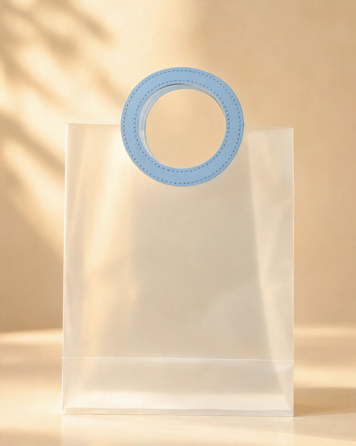 Frosted PVC gift bag with round blue handle, close front view