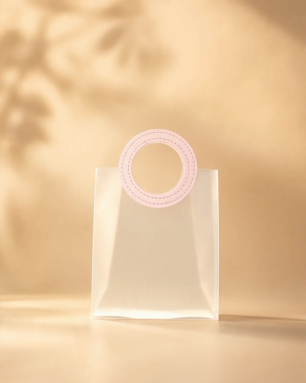 Clear PVC gift bag with pink round handle, closer front view