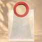 Clear PVC gift bag with red circular handle, closer front-facing view