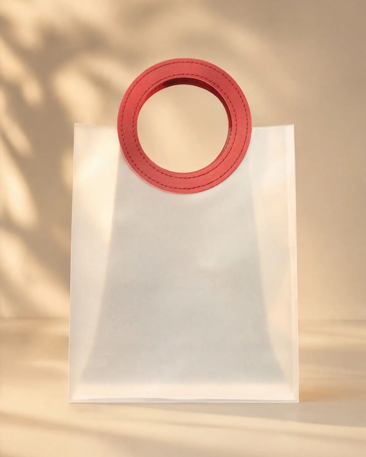 Clear PVC gift bag with red circular handle, closer front-facing view