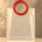 Detail close-up of the stitched red round handle on a clear PVC gift bag