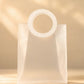 Frosted white PVC gift bag with round handle, front view under soft light