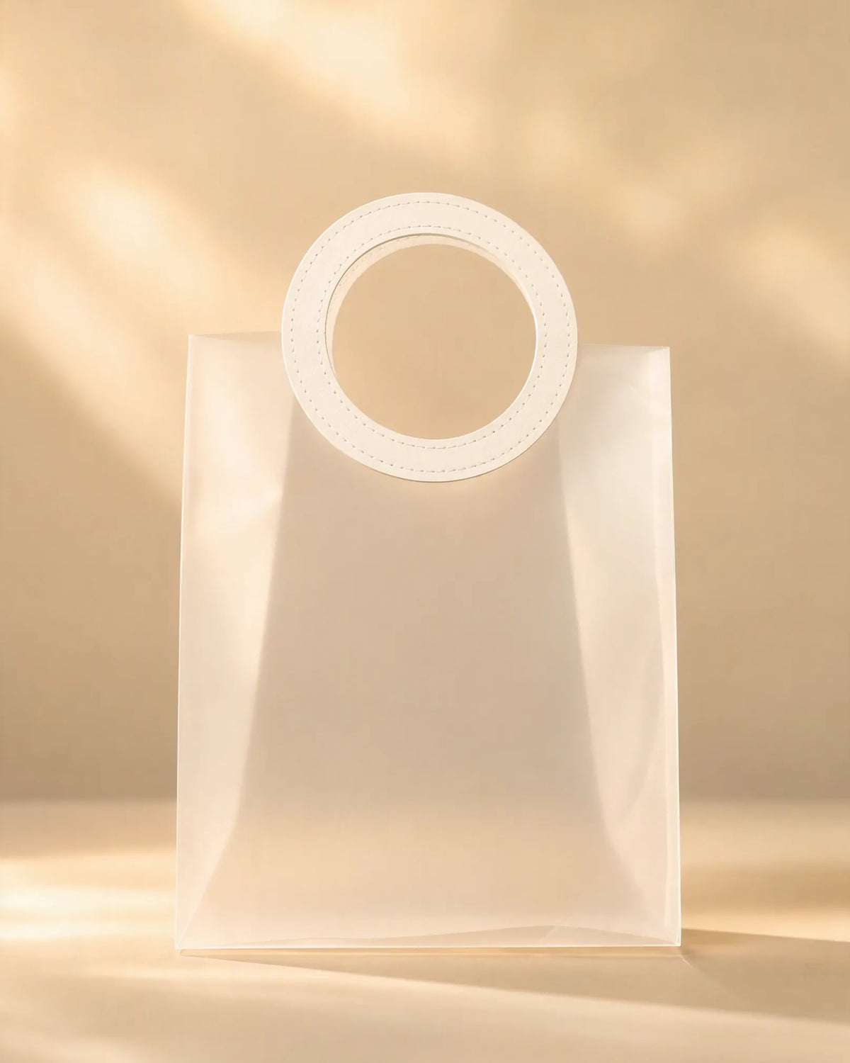 Frosted white PVC gift bag with round handle, front view under soft light