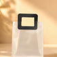 Frosted PVC gift bag with black square handle standing on flat bottom