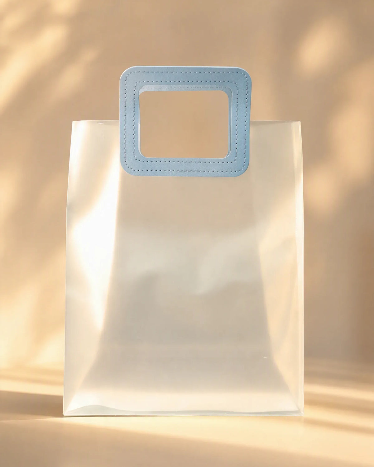 Clear PVC gift bag with a light blue square handle, closer front-on view