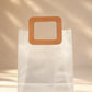 Frosted PVC gift bag with tan square handle, close-up front view