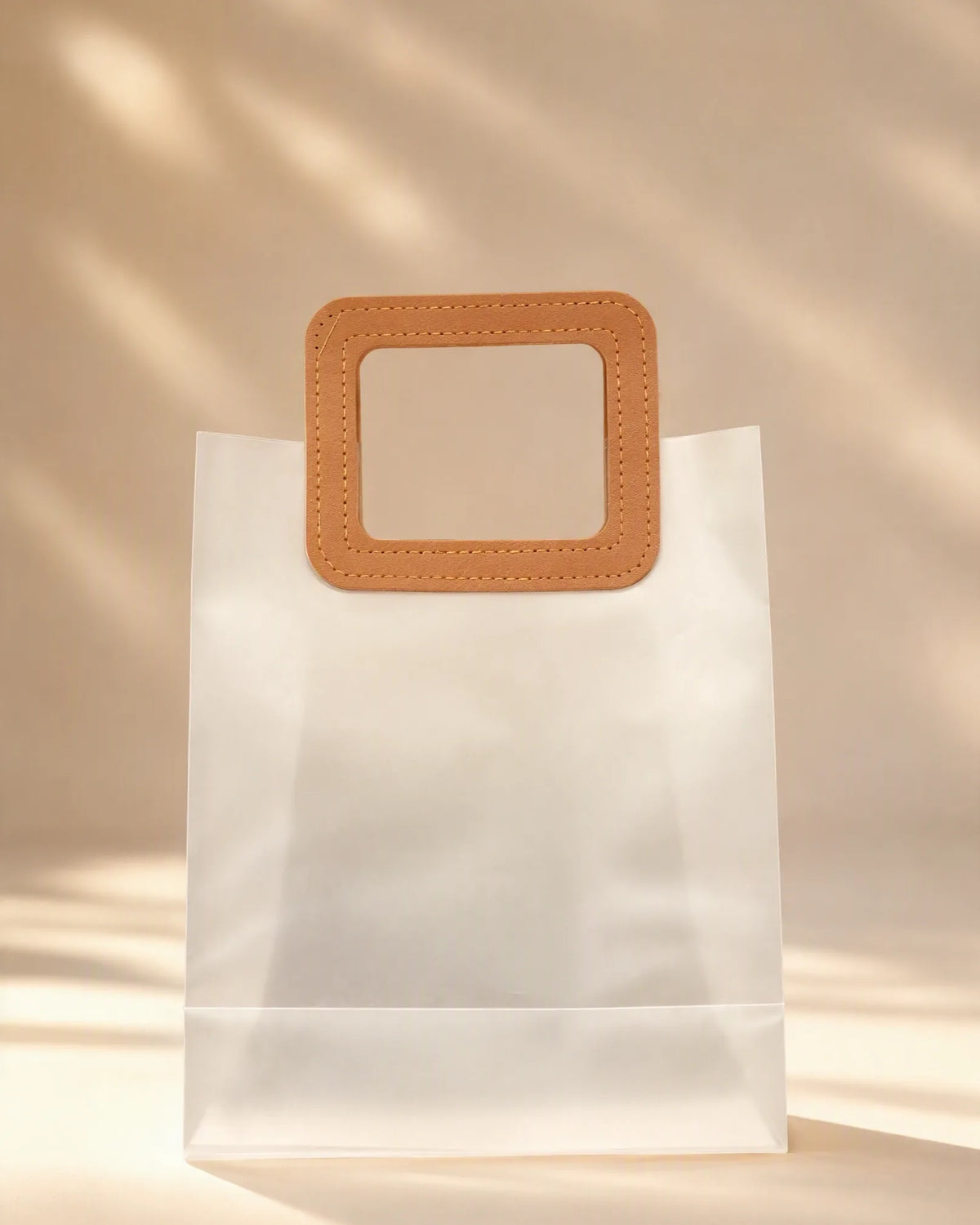 Frosted PVC gift bag with tan square handle, close-up front view