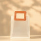 Frosted PVC gift bag with tan square handle, angled close-up of handle