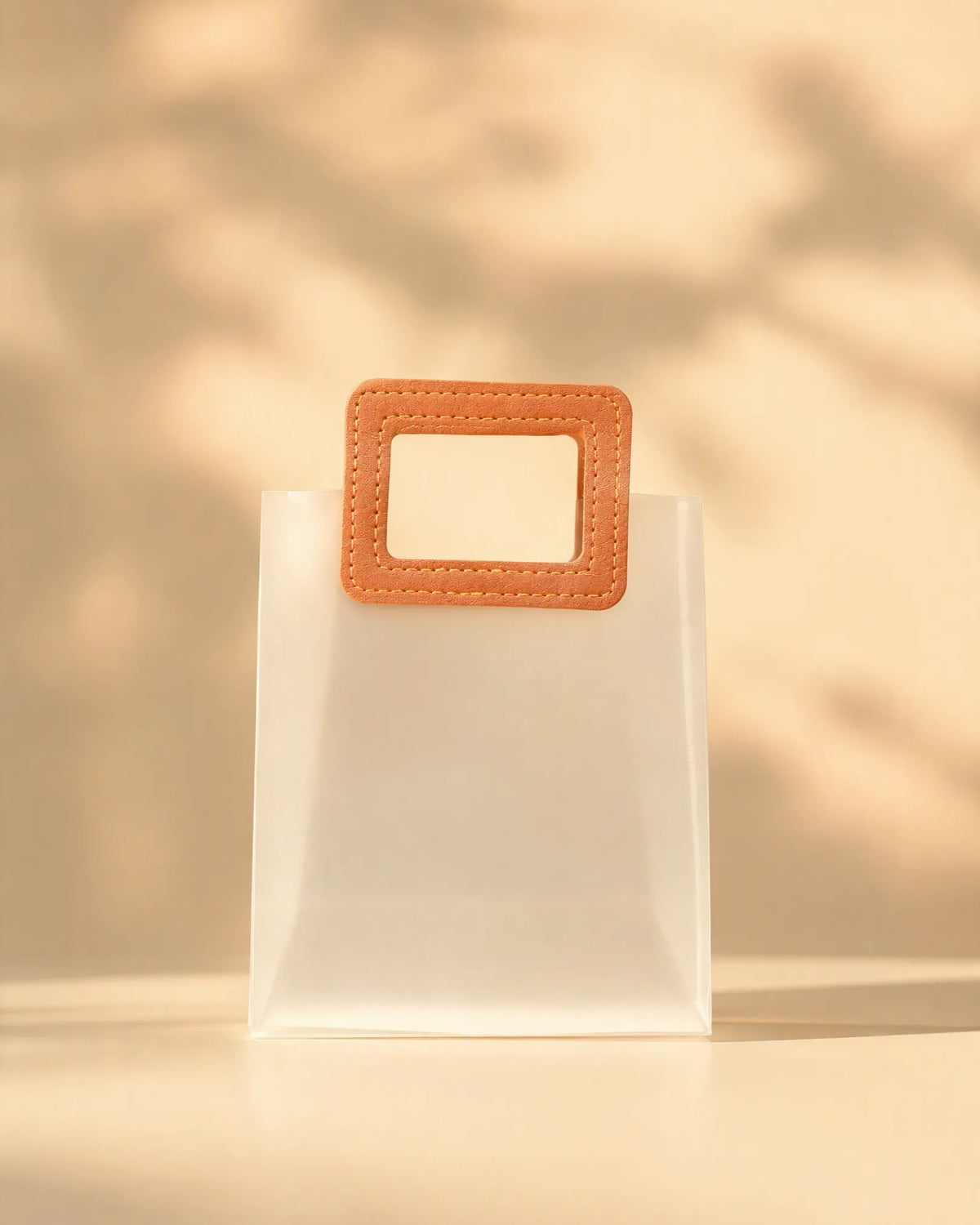 Frosted PVC gift bag with tan square handle, angled close-up of handle