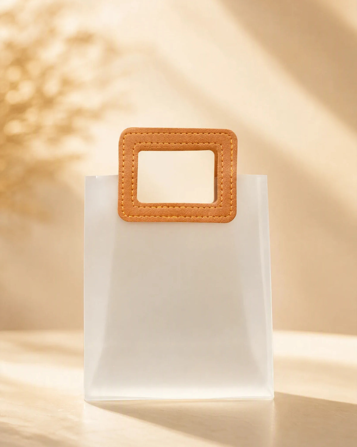 Frosted PVC gift bag with tan square handle, straight-on view