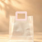 Clear PVC gift bag with pink square handle, size M, front view