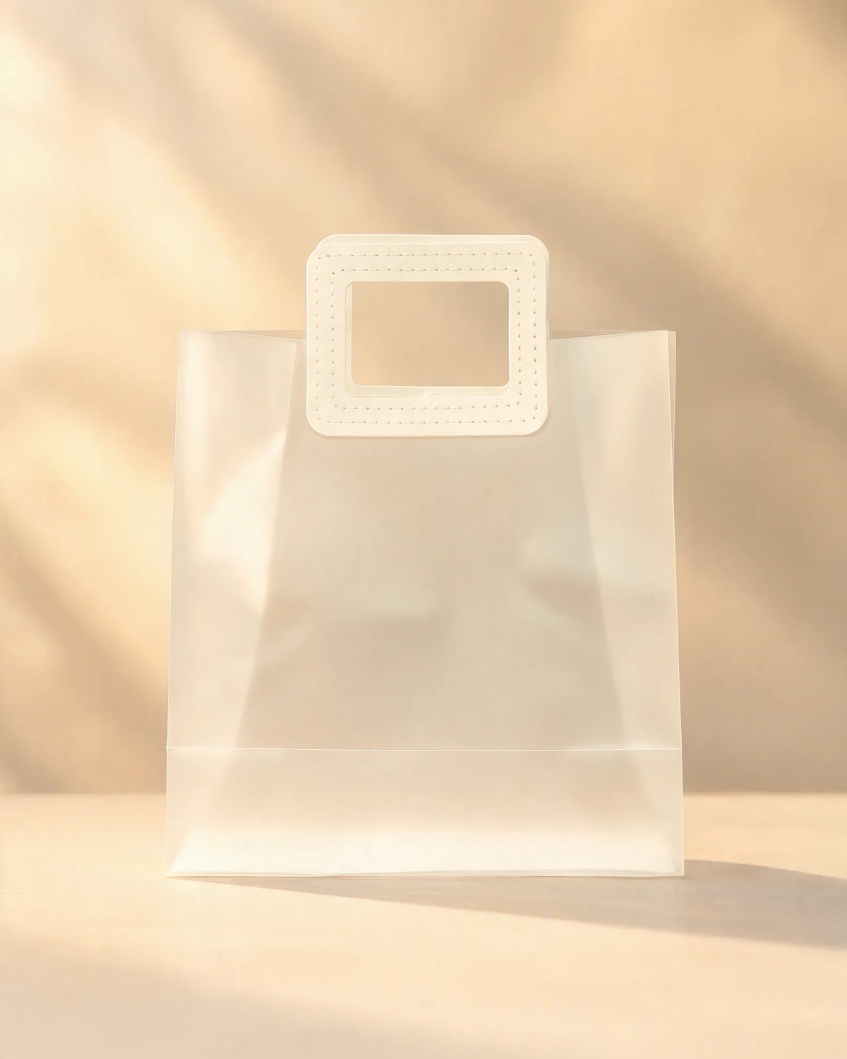 Clear PVC gift bag with off-white square handle, centered front view