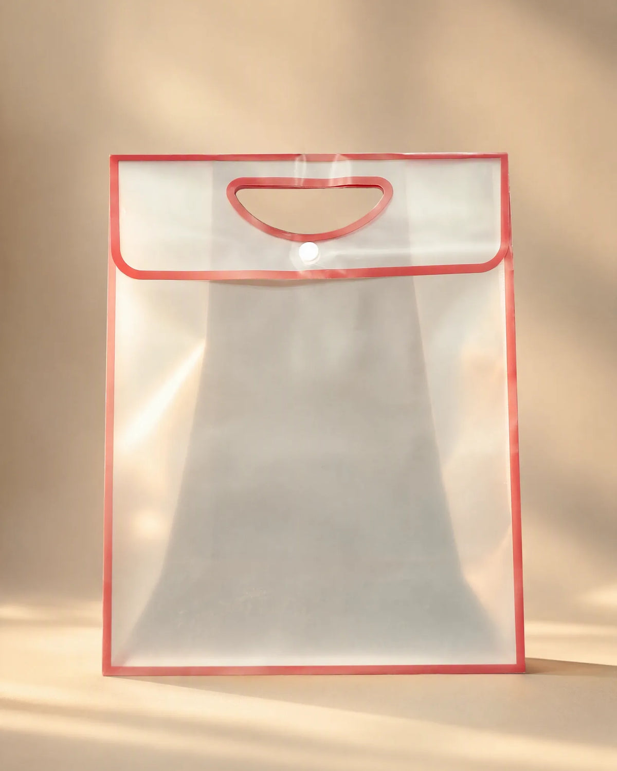 Clear PVC gift bag with red trim, cutout handle, and button closure
