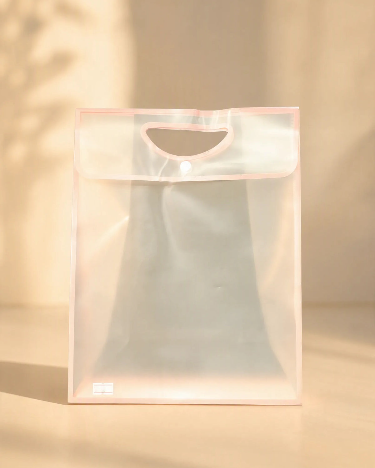 Frosted pink PVC gift bag with cutout handle and button closure