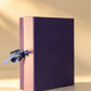 Purple and dusty rose two-tone gift box with blue ribbon bow, closed upright