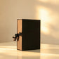 Black gift box with kraft-tone sides and black satin ribbon bow